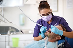 Dental hygienist using special tools to clean patient's teeth
