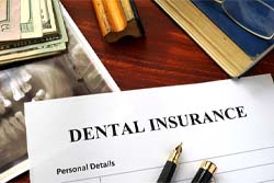 Dental insurance paperwork lying on desk with X-ray