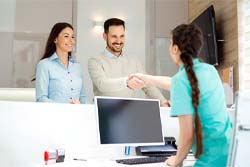 Man shaking hands with dental receptionist