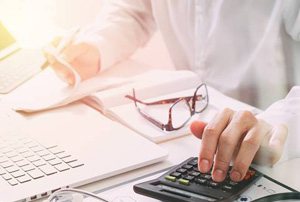 Person using a calculator and reviewing paperwork