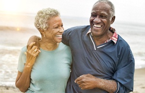 An older couple walking along the beach and enjoying their implant dentures in San Antonio