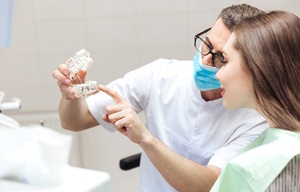 A dentist showing a female patient how dental implants work in San Antonio during a consultation