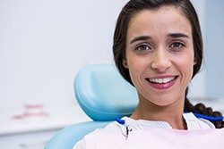 Woman smiling while looking at camera in dental chair with pony tail