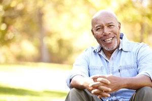 Older man in blue jacket sitting outside smiling