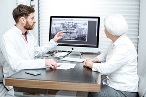 Bearded dentist showing female patient an X-ray