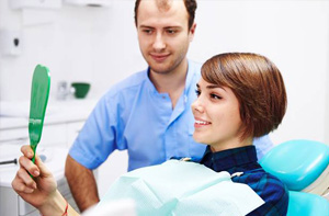 Smiling woman in dental chair holding mirror
