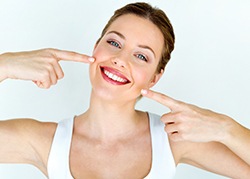 Woman pointing to her smile after teeth whitening in San Antonio, TX