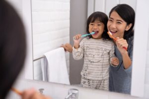 parent brushing their teeth with their child