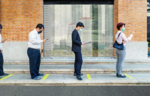 people social distancing outside of a building