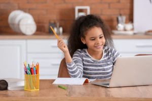 child sitting in front of a laptop doing virtual schooling 