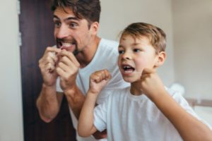 Father and son flossing as recommended by San Antonio pediatric dentist 