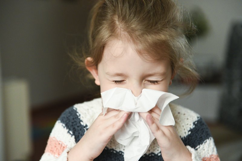 Closeup of child blowing her nose into tissue