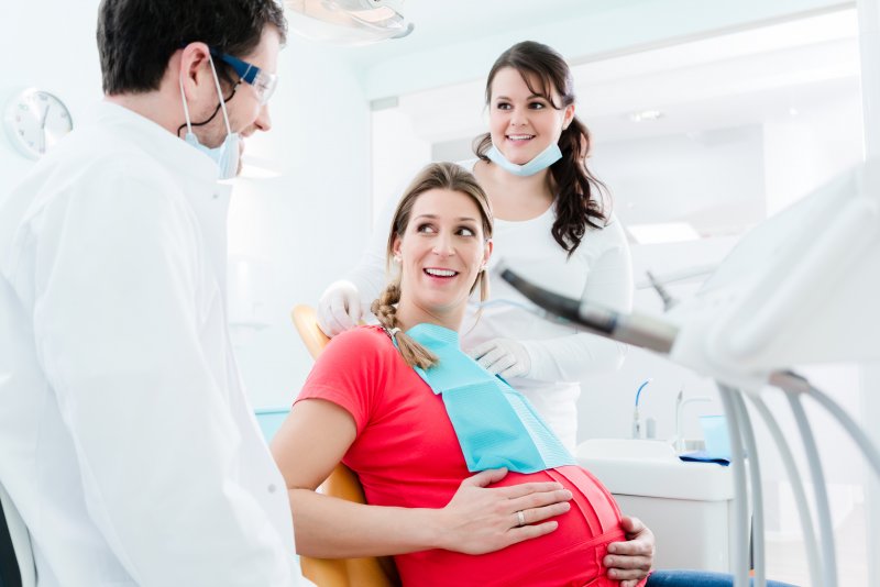 a pregnant woman sits in the dentist’s chair while listening to the experts explain what will happen during her appointment