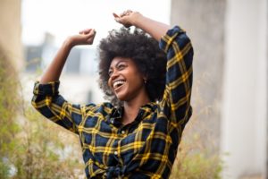 Woman smiling with implant dentures outside acting happy