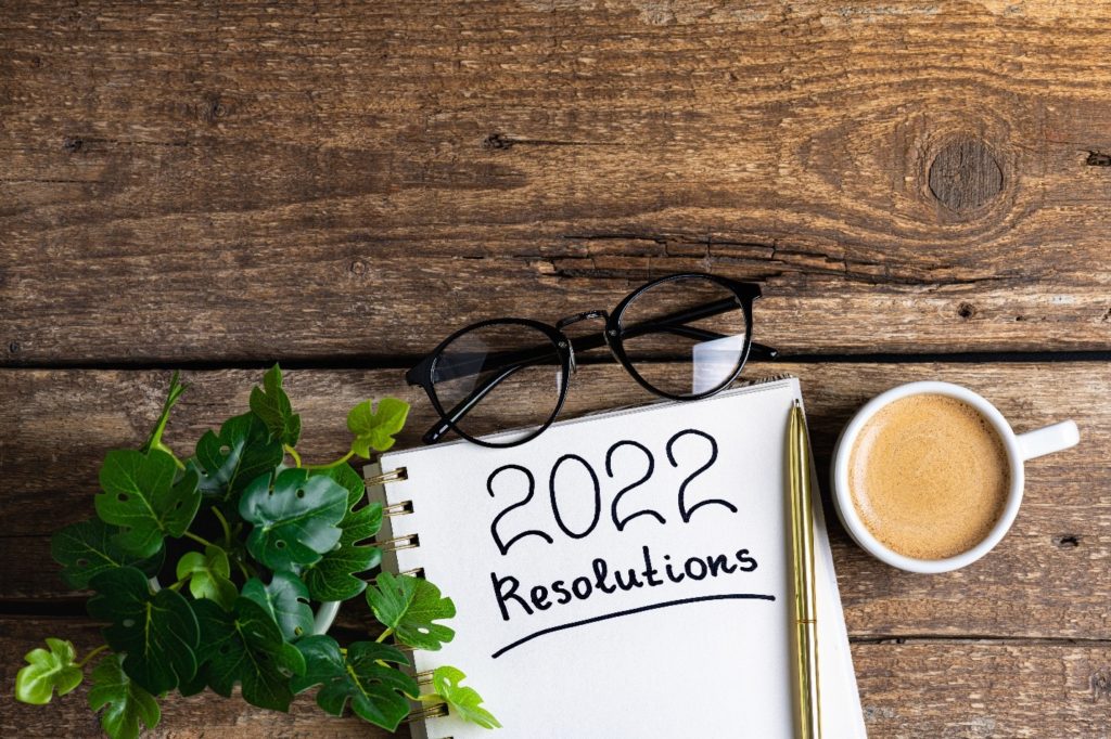 2022 resolutions on desk next to glasses, coffee, and plant