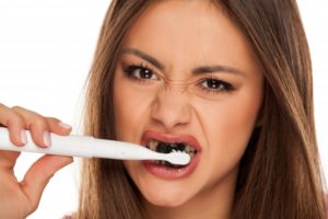 Woman brushing her teeth with charcoal