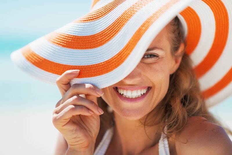 A smiling young woman in a swimsuit and beach hat