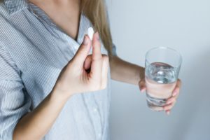 Woman holding a pill and glass of water