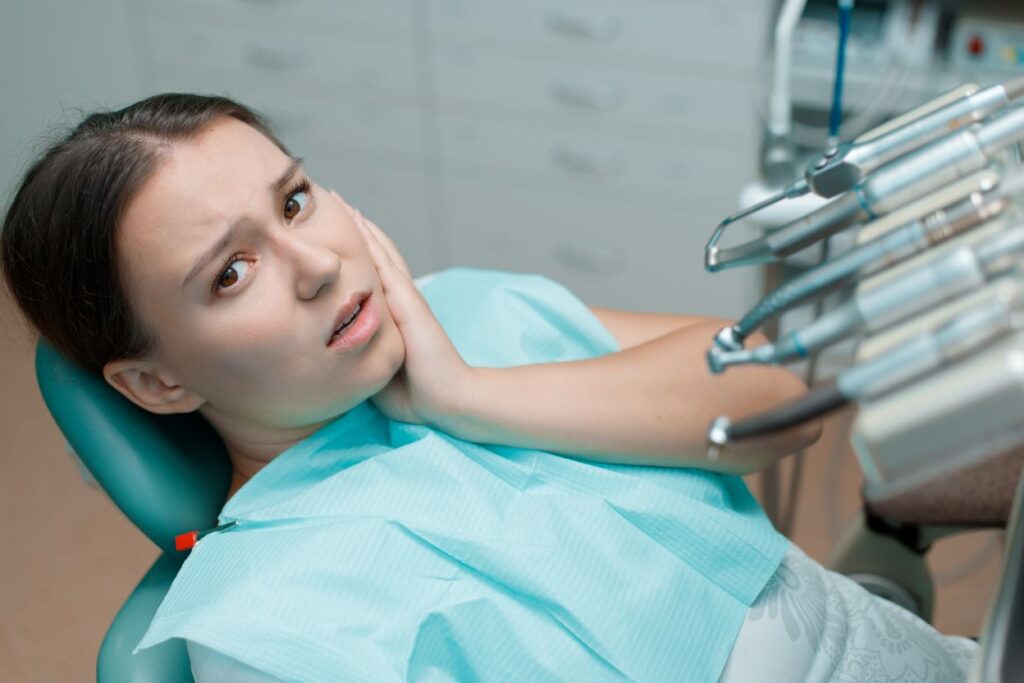 A young woman clutching her jaw in pain.
